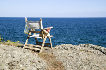 Old wooden chair on a rocky seashore