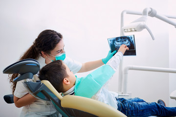 Doctor dentist and child in the office watching an x-ray. Dental treatment.