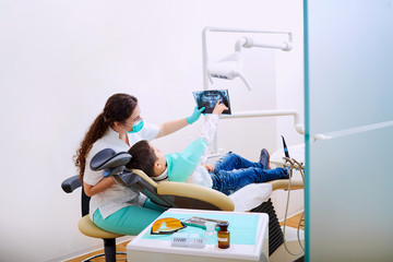 Doctor dentist and child in the office watching an x-ray. Dental treatment