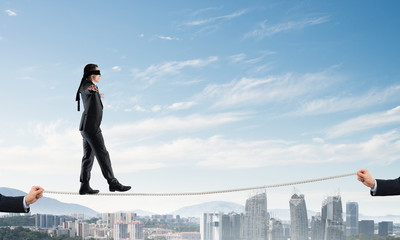 Business concept of risk support and assistance with man balancing on rope