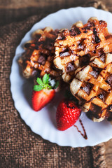 Belgian waffles topped with strawberries, syrup and icing. Homem