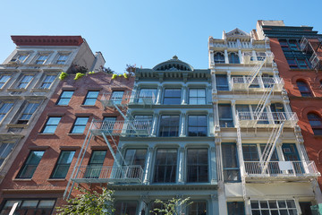 New York houses facades with fire escape stairs, sunny day in Soho - obrazy, fototapety, plakaty