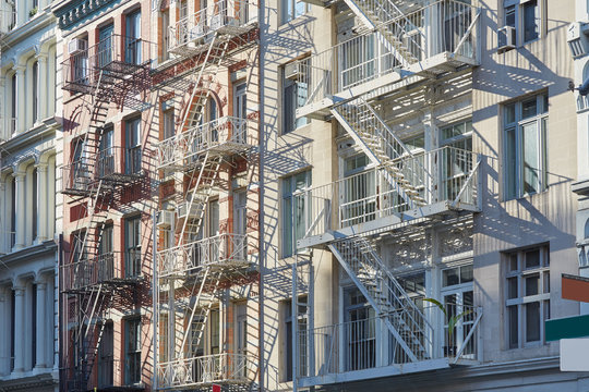 Houses facades with fire escape stairs background, sunlight in New York