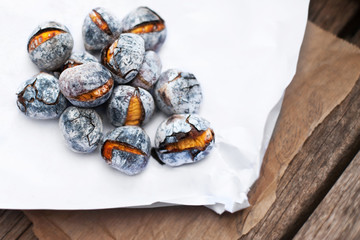 Roasted chestnuts served on white and brown craft paper with cop