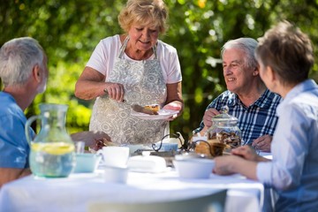 Senior woman serving breakfast in garden