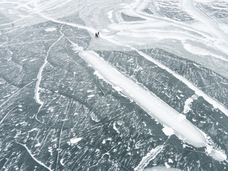 Three people walking across icy frozen lake, elevated view