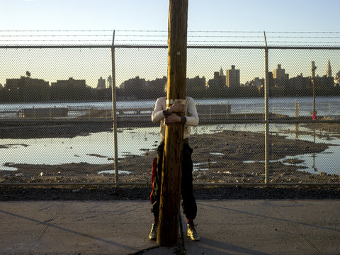 Person hiding behind telegraph pole with cityscape in background