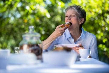Senior woman eating sweet food in garden