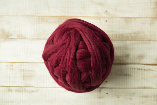 Red merino wool ball on wooden background