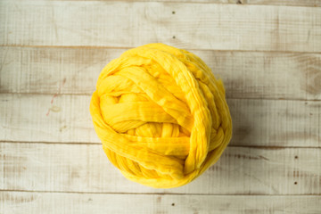 Yellow merino wool ball on wooden background