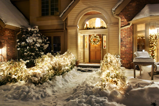 Christmas decorations and lights line front path and patio in the snow