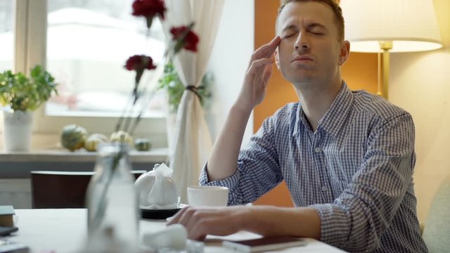 Man sitting by the table in the cafe and look very tired
