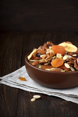 Healthy dried fruits and nuts in bowl on wooden background.