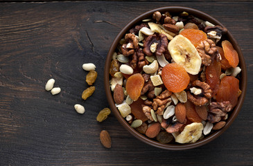 Nutritious dried fruits and nuts in bowl on wooden background.