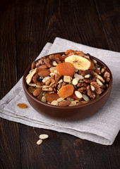 Dried fruits and nuts in a bowl on rustic table.