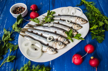 herring fish with greens on a wooden blue background. Top view. Close-up