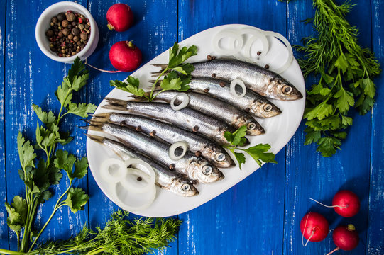 herring fish with greens on a wooden blue background. Top view. Close-up