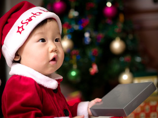 Asian baby girl in a Santa costume with a gift box