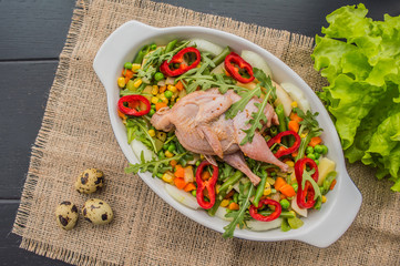 Marinated quail with vegetables for subsequent cooking in the oven. In the Black wooden background. Close-up