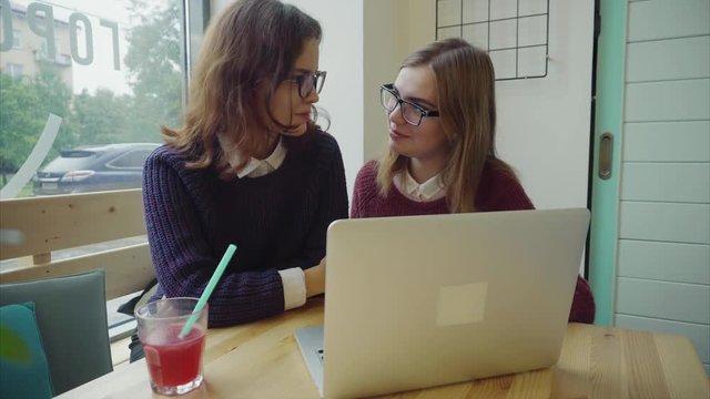 Two girls talking to friends via webchat or having a video chat in cafe 4K