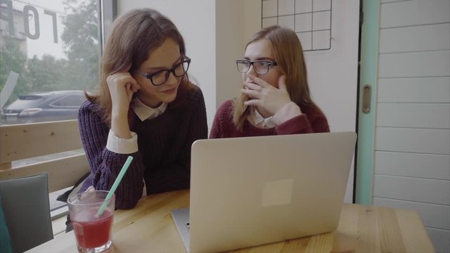 Two girls talking to friends via webchat or having a video chat in cafe 4K