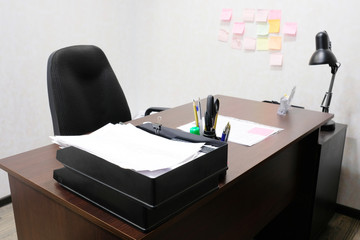 Interior of an office room with chair, table, lamp and stationery on it