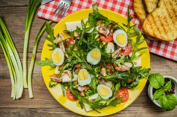 Warm salad with bacon and arugula. Wooden rustic background. top view