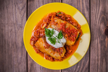 Dinner with cabbage rolls in tomato sauce decorated  parsley. Wooden rustic background. Top view. Close-up