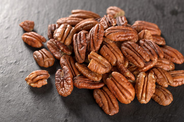 Peeled pecan nuts on a slate plate, selective focus