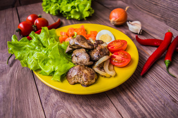 Chicken liver and quail eggs for dinner. On a brown wooden background. Close-up