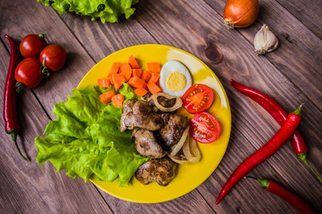 Chicken liver and quail eggs for dinner. On a brown wooden background. Close-up