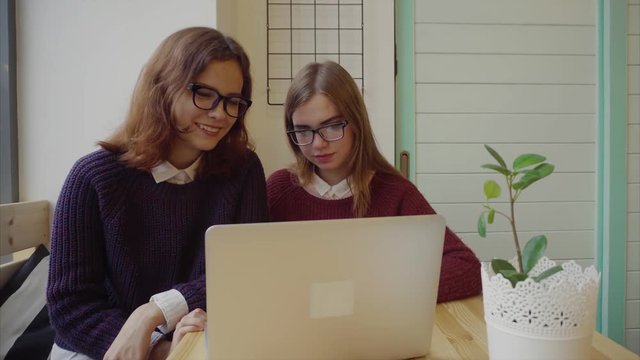 Two girls talking to friends via webchat or having a video chat in cafe 4K
