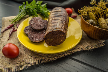 Homemade blood sausage with offal on a black wooden background. Close-up