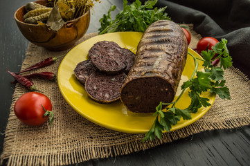 Homemade blood sausage with offal on a black wooden background. Close-up