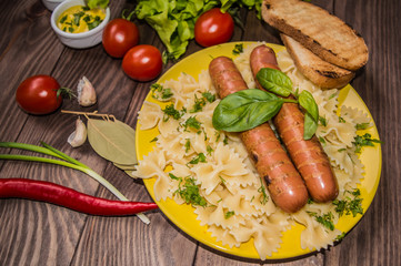 Grilled sausage with pasta, slices of bread, herbs and cherry tomatoes. Top view. On a wooden rustic brown background. Close-up