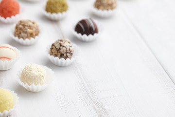 Chocolate truffle candies on white wooden background, space for texting