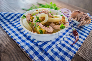 Ready fresh squid rings and tentacles of an octopus with stewed potatoes  greens in rustic. Top view. Close-up