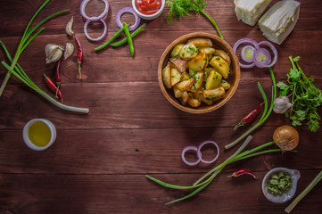 Roasted potatoes with vegetables and herbs on a wooden background, top view. Close-up