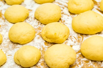 Raw donuts lying in flour on wooden table