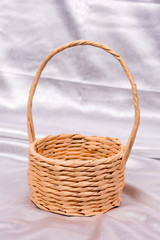 Fototapeta na wymiar Woven basket for flower arrangement over white satin. Beautiful
