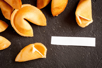 Chinese fortune cookie with prediction on dark background top view