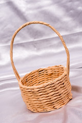 Woven basket for flower arrangement over white satin. Beautiful