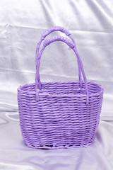 Fototapeta na wymiar Purple rustic woven basket over white satin