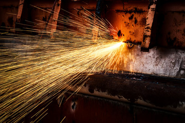 hot golden sparks flying from worker to cutting steel in a construction site with oxygen-propane...