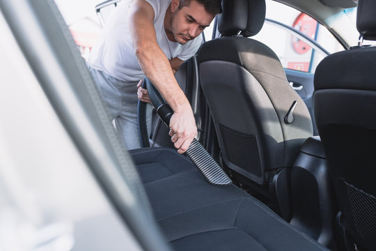 Mature Man Cleaning With Vacum Cleaner Interior Of Luxury Car. 