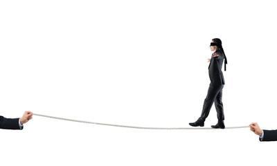 Young businessman in blindfold against white background walking on rope
