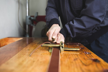 Close up shot of worker's hands in leather belt making process. 