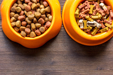 dry dog food in bowl on wooden background top view