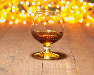 Glass of brandy or cognac and candle on the wooden table