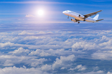 airplane flying away in to sky high altitude above the white clouds with sunlight